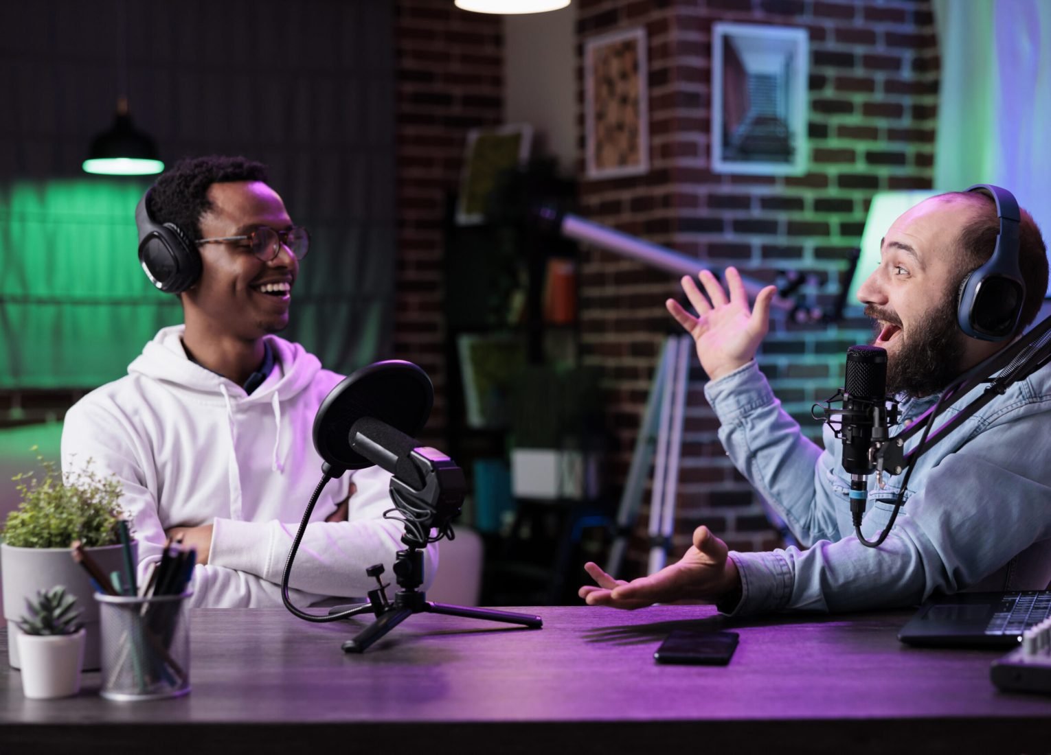 POV of male bloggers vlogging podcast talk on camera, using streaming equipment in studio with neon lights. Content creators having fun filming online episode for social media.